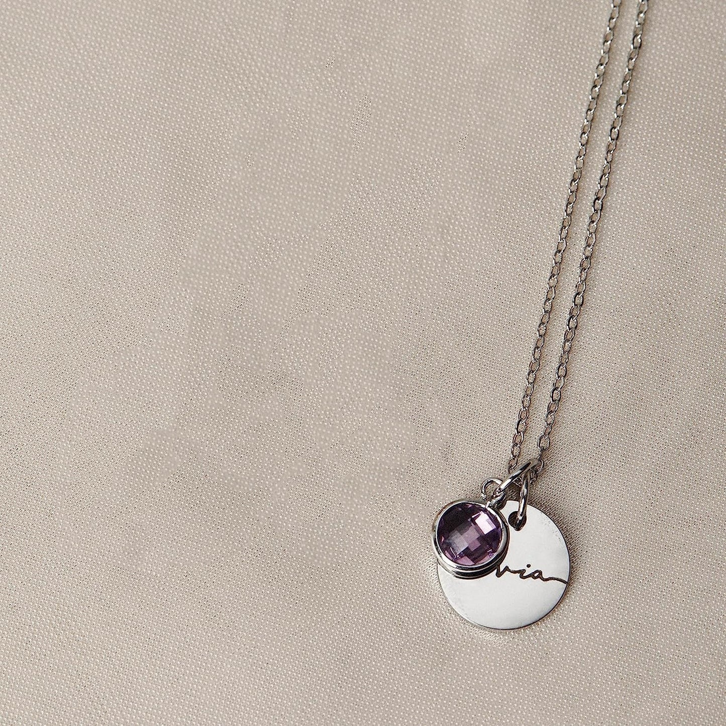 Necklace with a round pendant and amethyst stone on a beige background