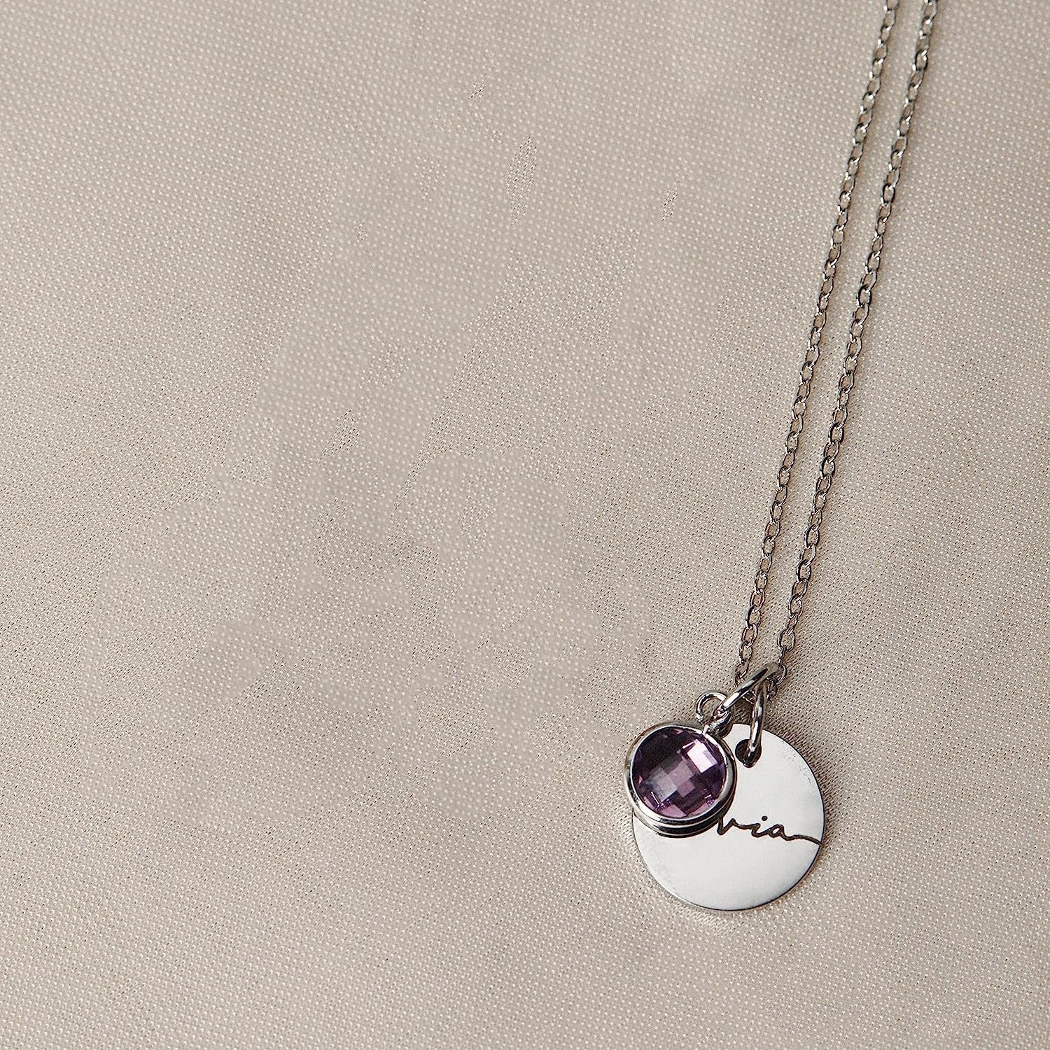 Necklace with a round pendant and amethyst stone on a beige background