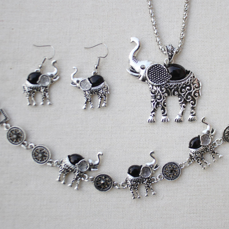 Jewelry set with elephant-themed necklace, bracelet, and earrings on a light gray background