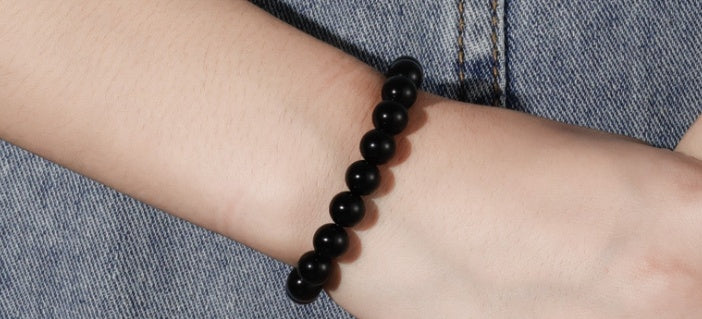 Black onyx beaded bracelet on a wrist with a denim background