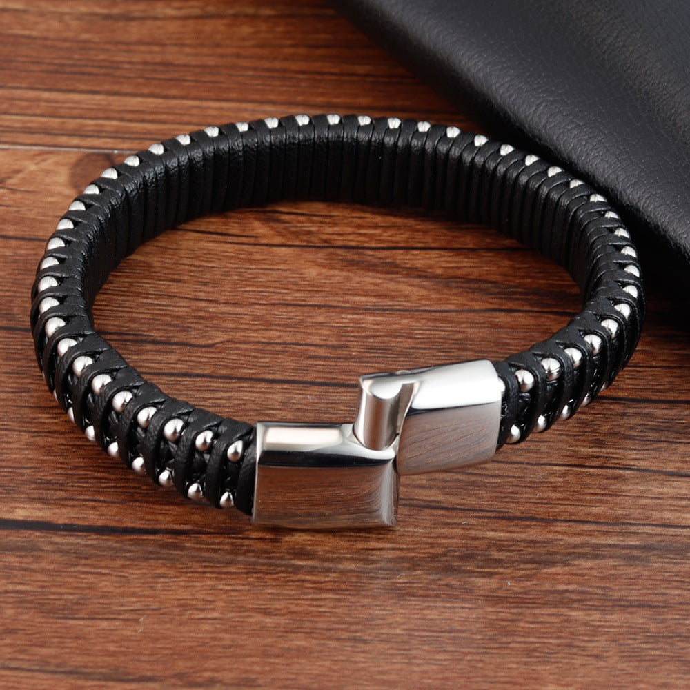 Black braided leather bracelet with silver clasp on a wooden surface