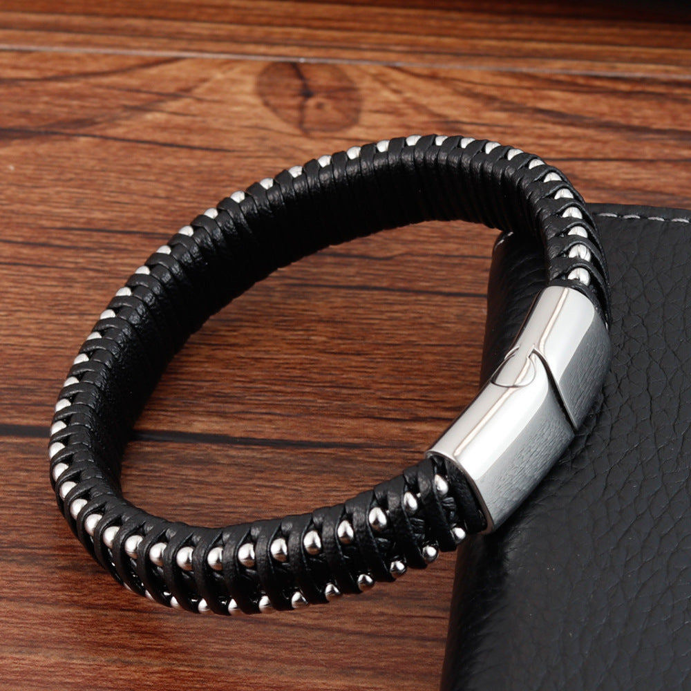 Black leather bracelet with silver studs on a wooden surface