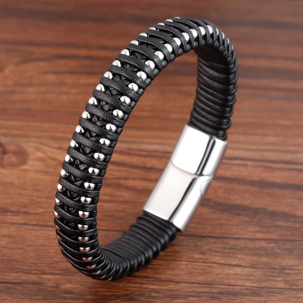 Black braided bracelet with silver beads and clasp on a wooden surface