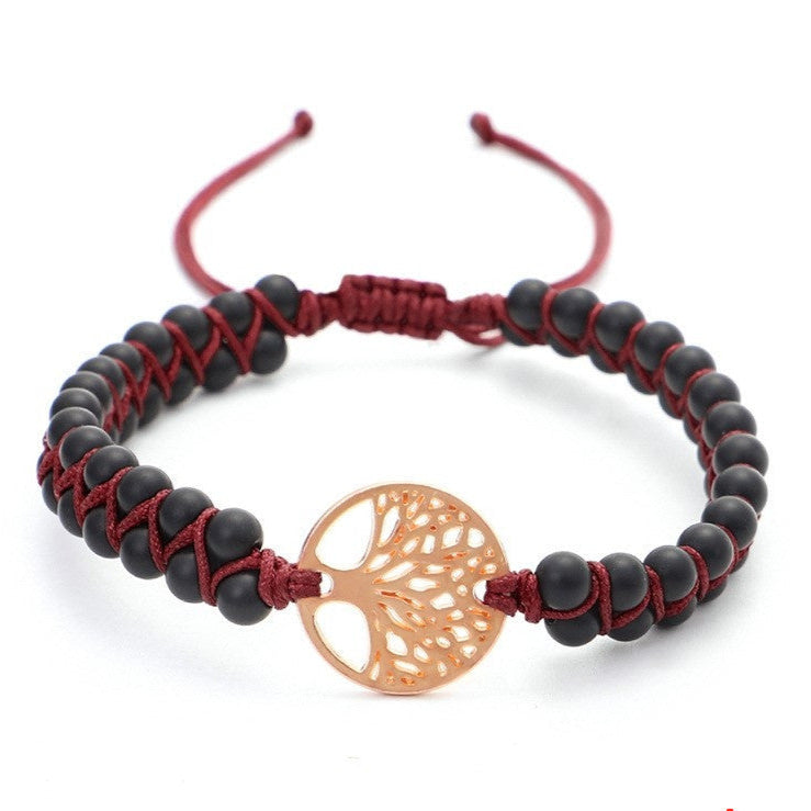 Bracelet with black beads, red cord, and gold tree-shaped charm on a white background