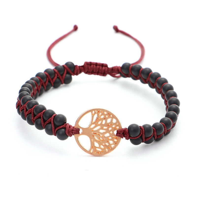 Bracelet with black beads and a rose gold tree of life charm on a white background