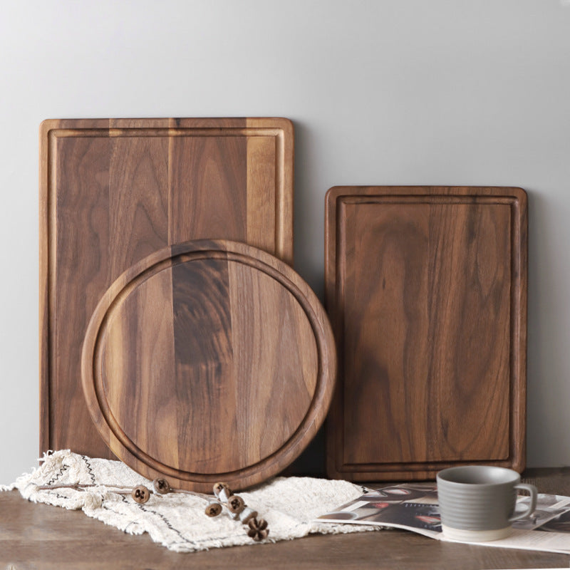 Three wooden cutting boards of different shapes on a table with a cup and magazine.