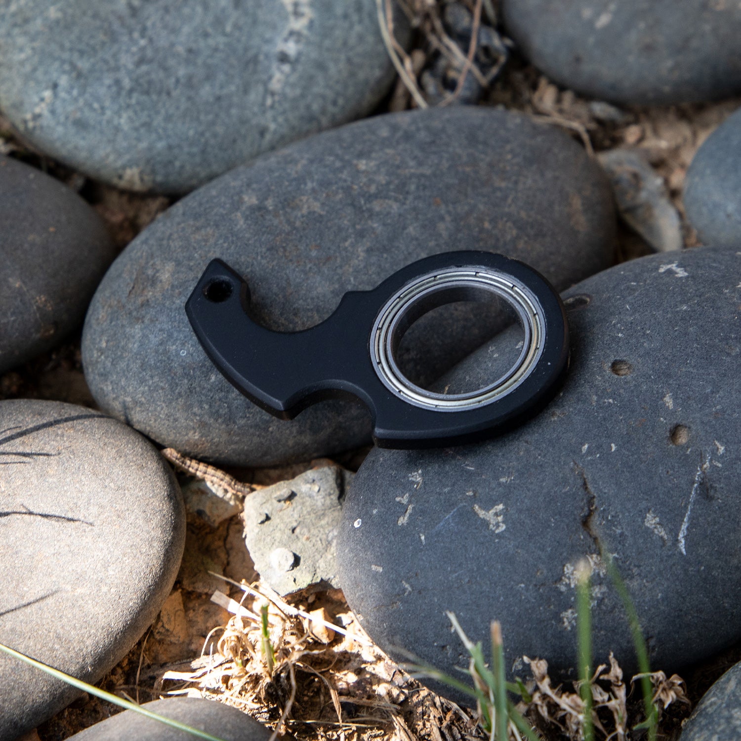 Black fidget spinner on a bed of gray stones