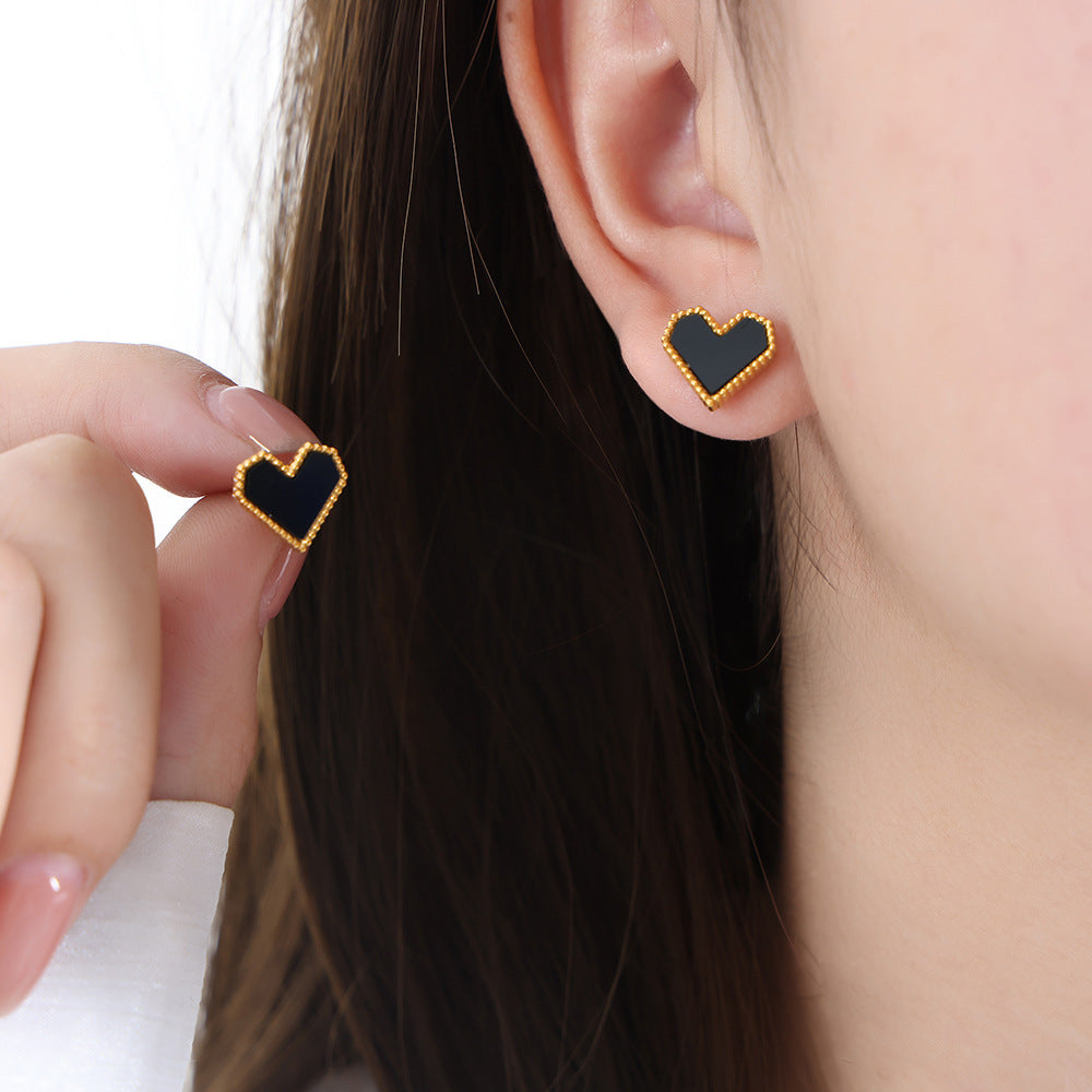 Black heart-shaped earrings worn by a person with dark hair.