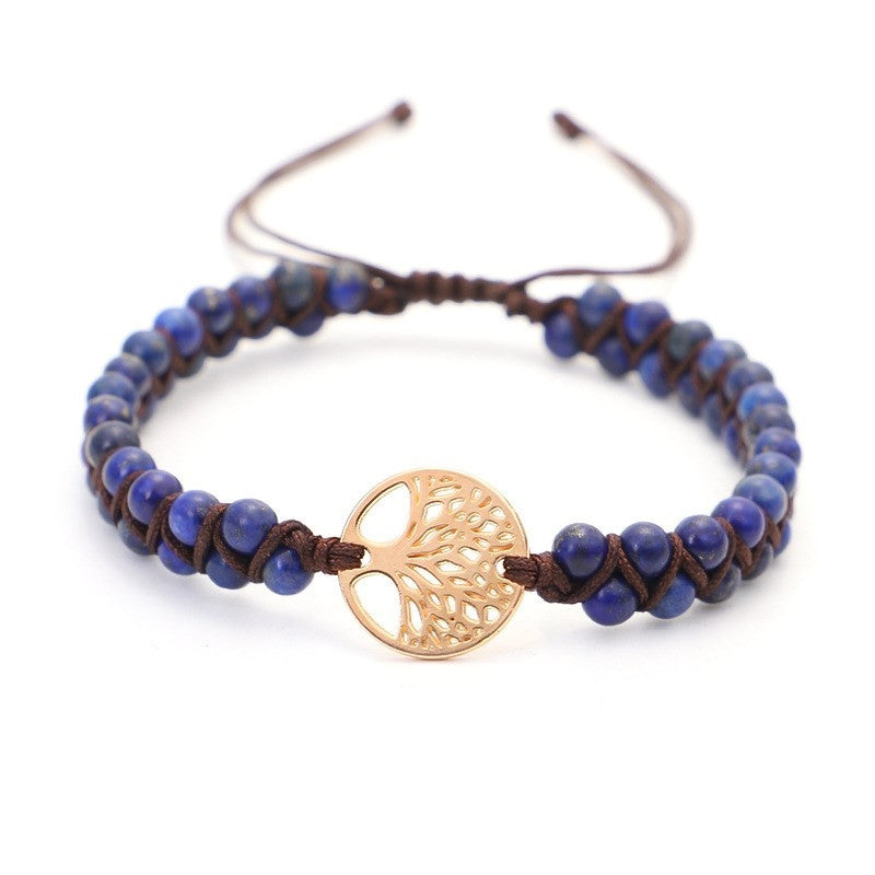 Bracelet with blue beads and a gold tree-of-life charm on a white background