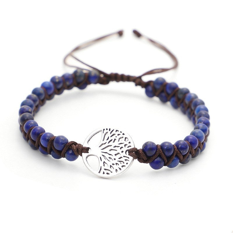 Blue beaded bracelet with a silver tree of life charm on a white background