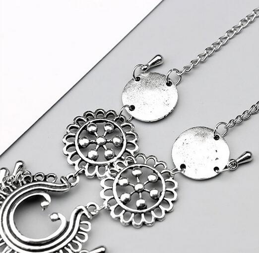 Silver necklace with intricate designs on a light gray background