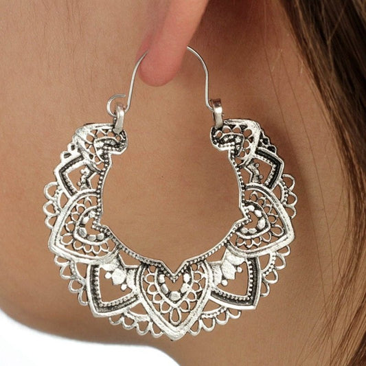 Silver filigree hoop earrings being worn on an ear