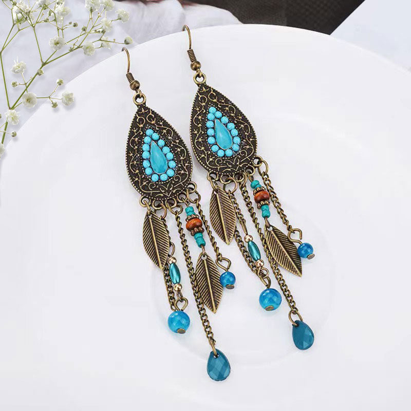 Bohemian-Tribal-Fringe-Earrings-Pair of earrings with turquoise stones and bronze detailing on a white surface.