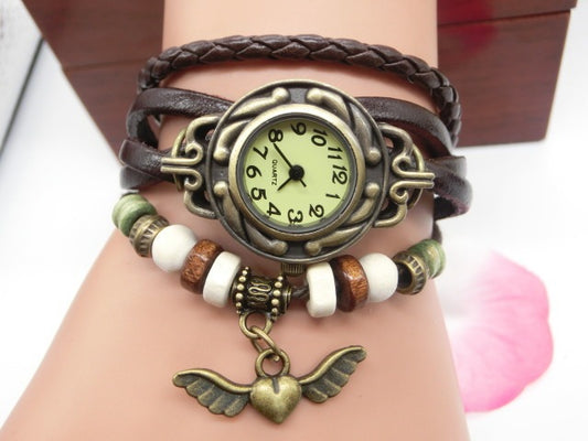 Bracelet with vintage-style watch and heart pendant on wrist against a neutral background