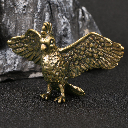 Brass bird figurine on a dark surface with a stone background