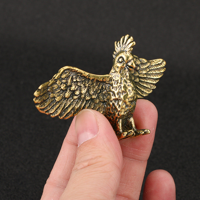 Brass parrot figurine held in a hand against a dark background