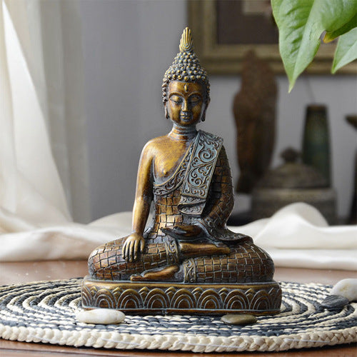 Bronze Buddha statue on a woven mat with a blurred indoor background