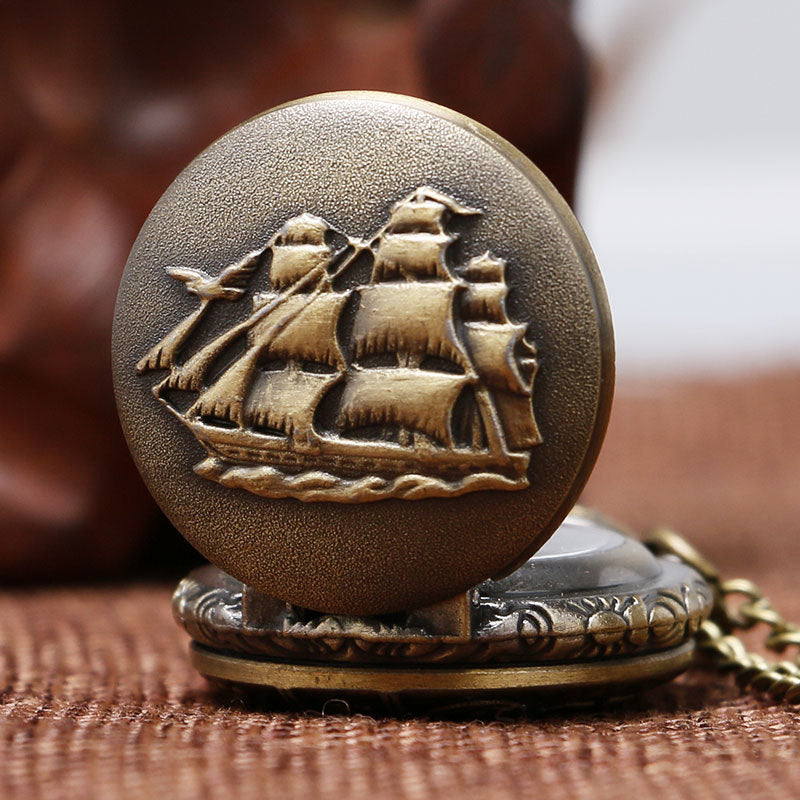 Bronze pocket watch with ship emblem on a brown textured surface