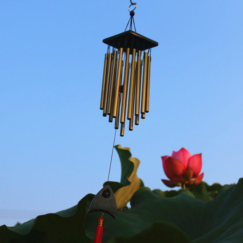 Wind chime with red flower and green leaves against a blue sky