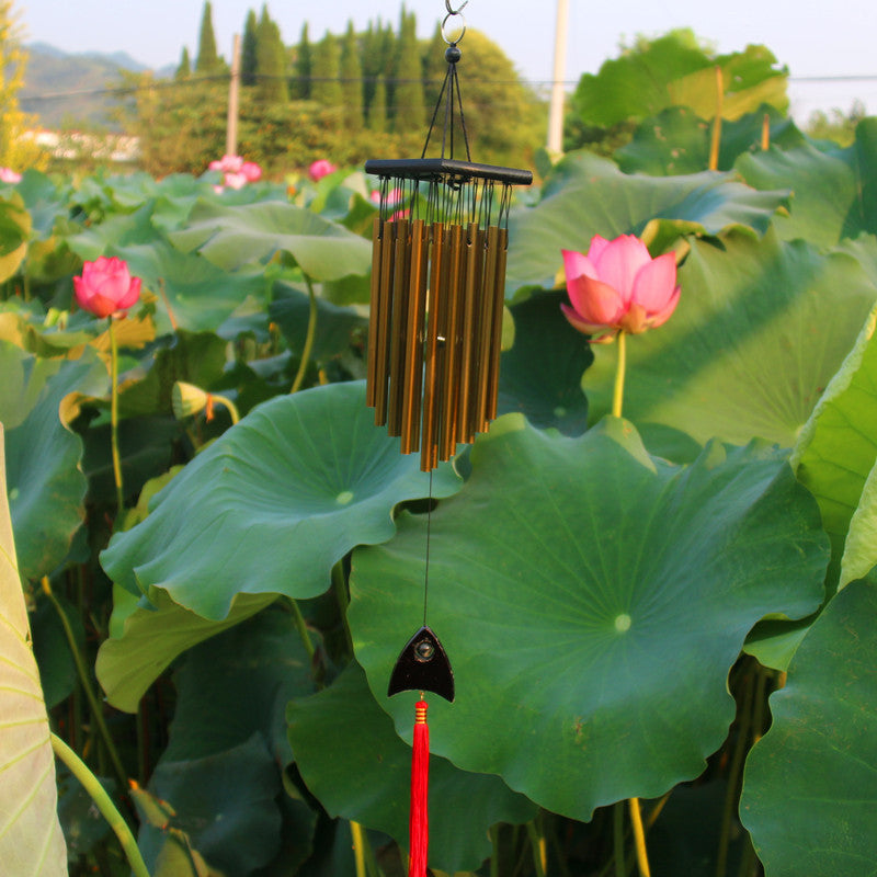 Wind chime hanging among lotus leaves with pink flowers