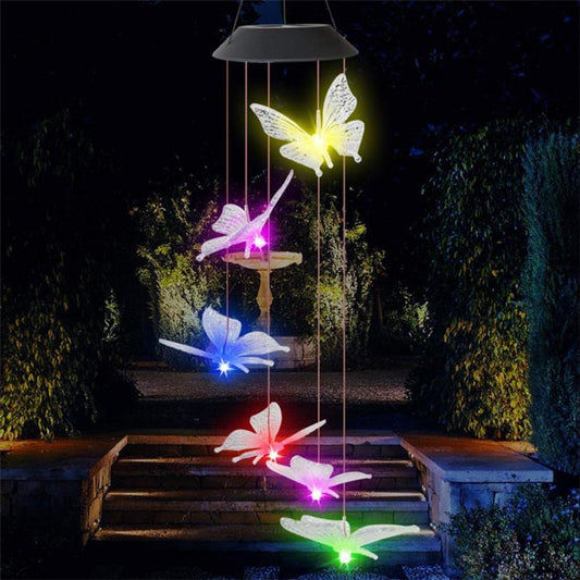 Colorful butterfly-shaped solar mobile hanging outdoors with a dark background.