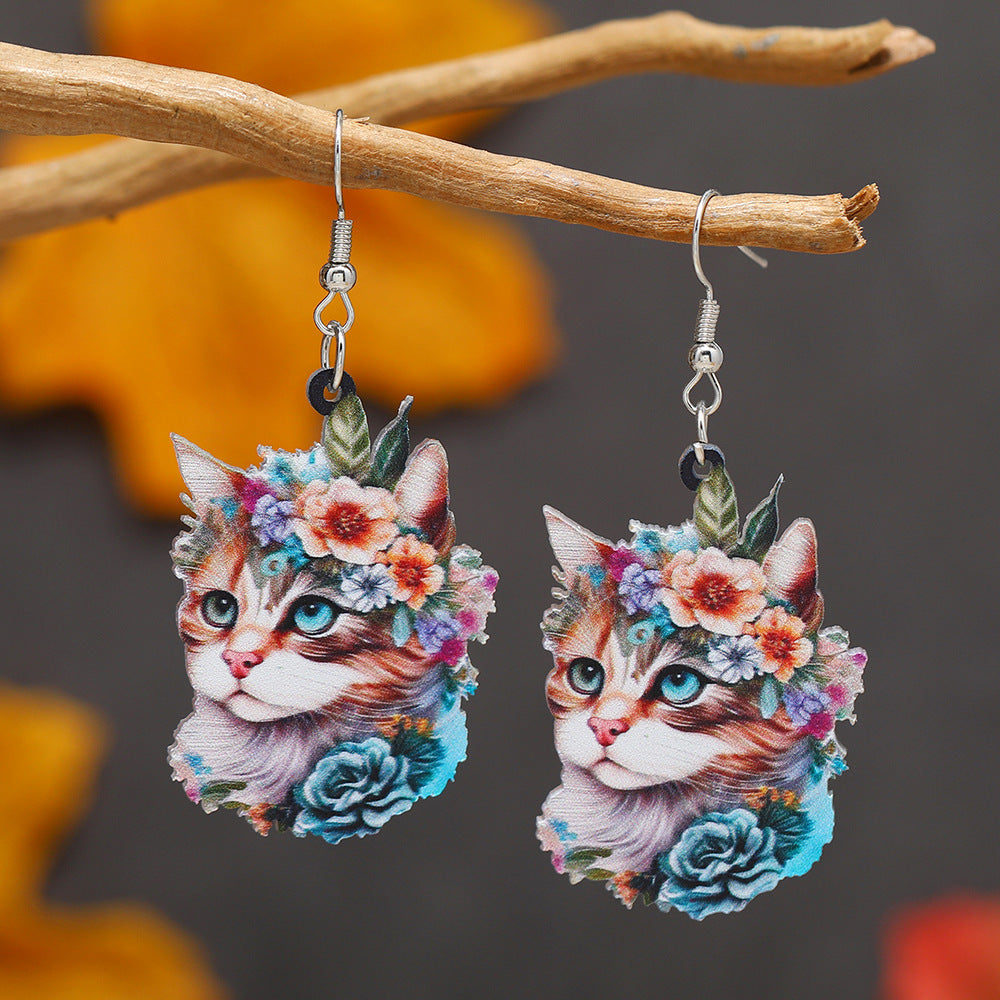 Cat-themed earrings with floral designs on a branch with orange leaves.