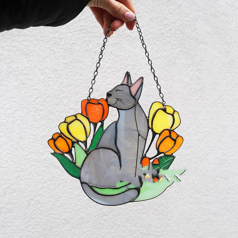 Stained glass panel of a cat among flowers held by a hand on a white background