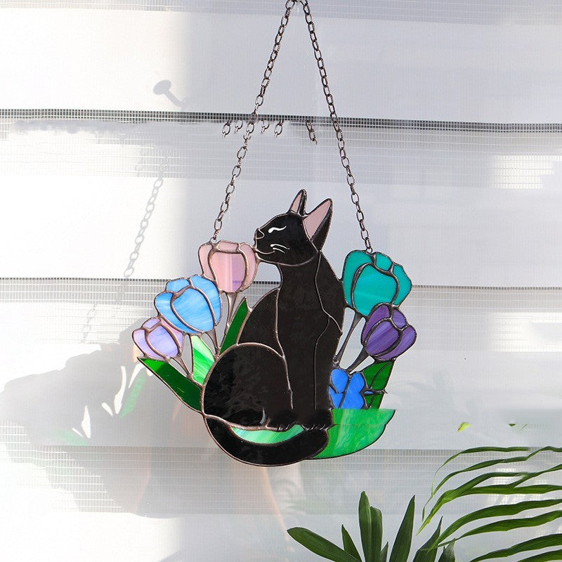 Stained glass panel with a black cat and colorful flowers hanging on a window.
