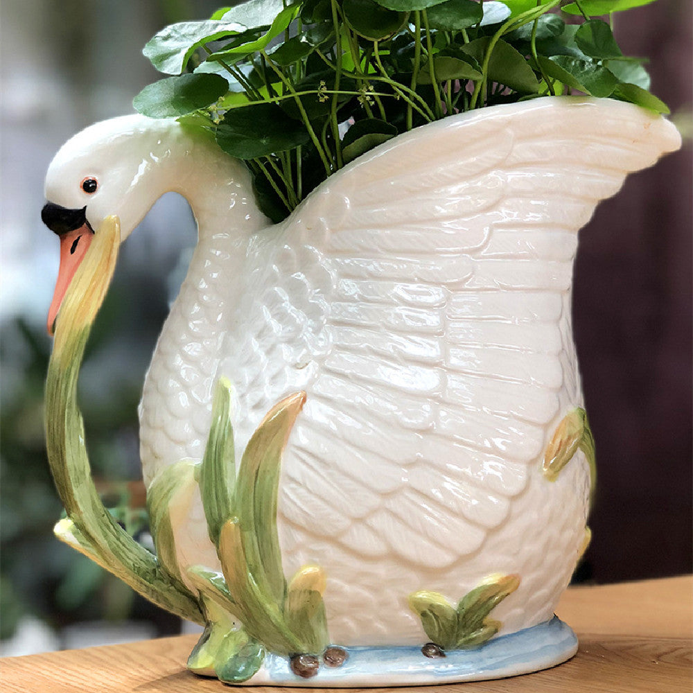 Ceramic swan planter with greenery on a wooden surface