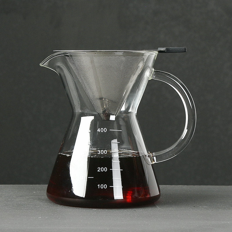 Clear glass coffee maker with a dark liquid inside on a gray surface and dark background