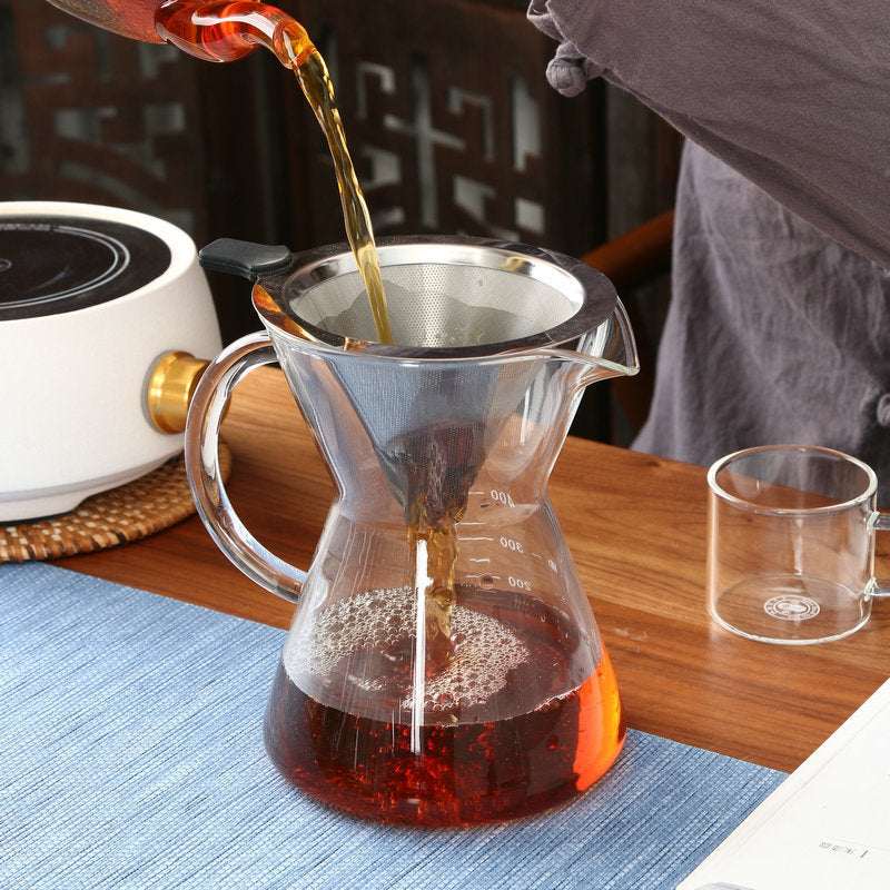 Pouring coffee from a carafe into a filter on a wooden table.