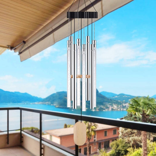 Wind chime hanging on a balcony with a scenic view of mountains and water.