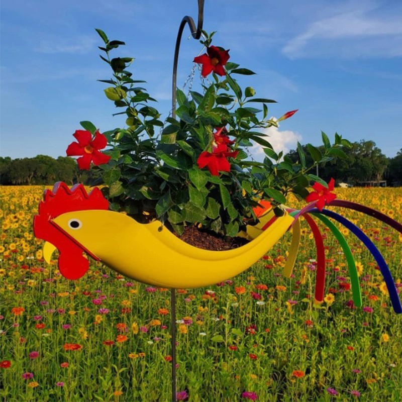 Colorful rooster-shaped planter with flowers against a blue sky and green field background
