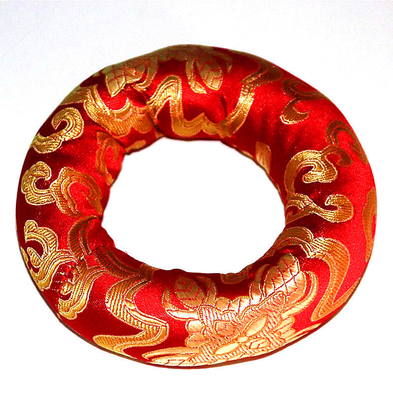 Red circular object with gold patterns on a white background