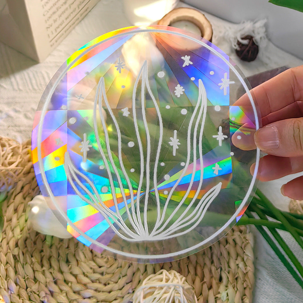 Holographic clear disc with white floral design held by a hand on a textured surface.