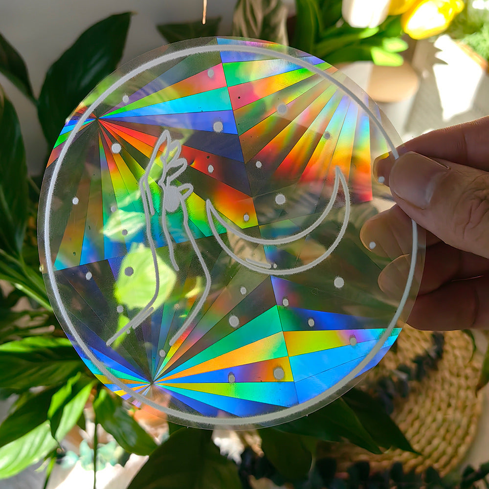 Colorful geometric suncatcher held by a hand with plants in the background