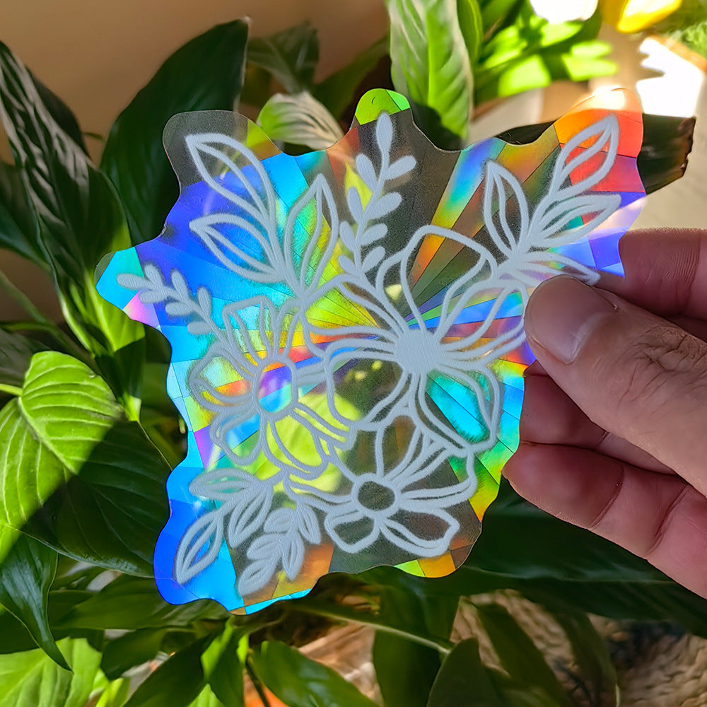 Holographic snowflake-shaped object held by a hand with green leaves in the background