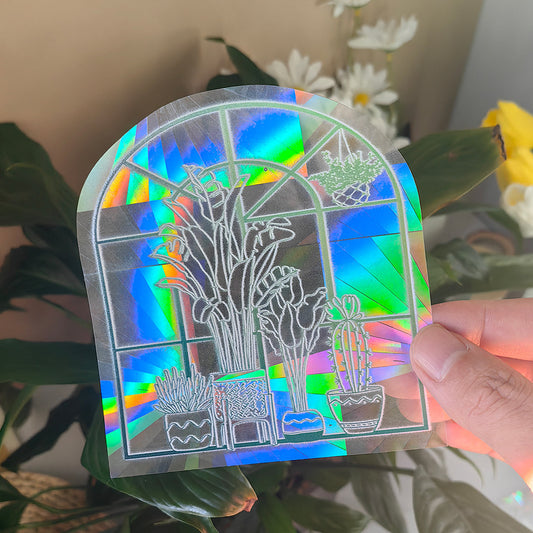 Holographic plant-themed card held in front of a plant and flowers