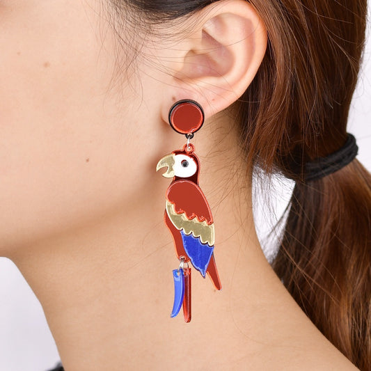 Colorful parrot-shaped earring worn by a person with a neutral background