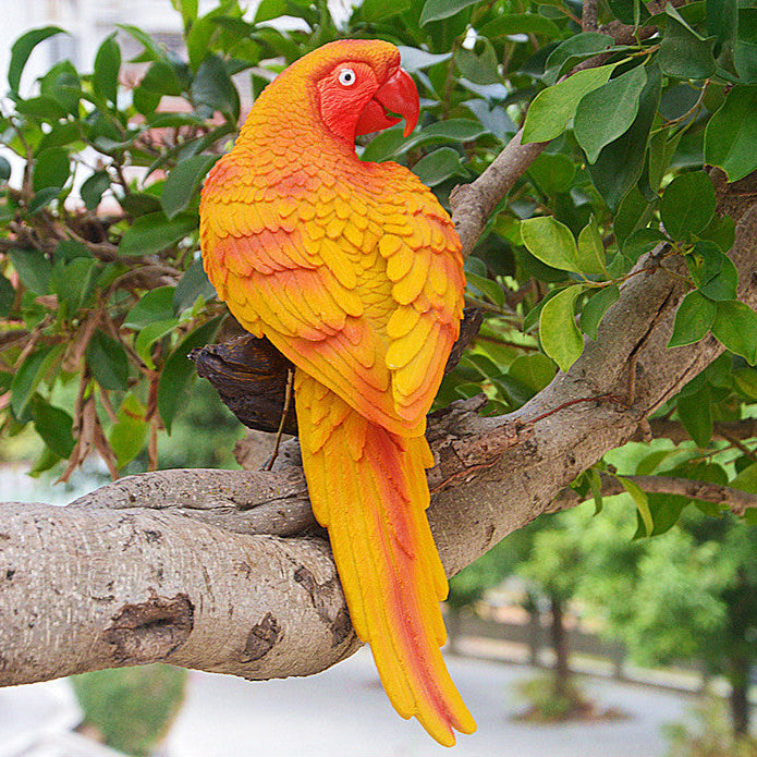Colorful parrot figurine on a branch with green foliage in the background