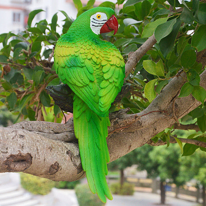 Green parrot figurine on a branch with a blurred green background