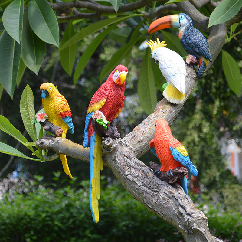 Colorful parrot figurines on a branch with a natural green background