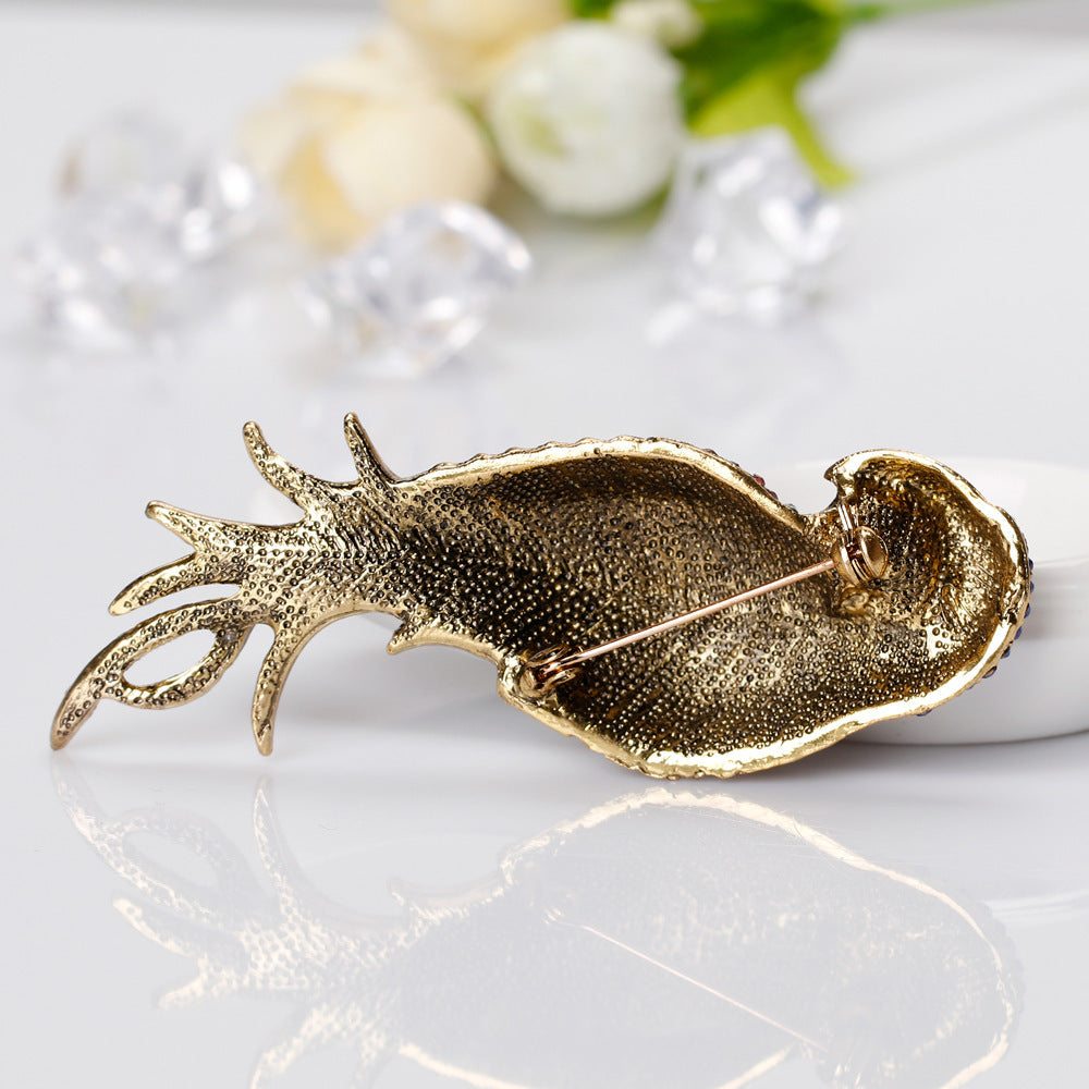 Gold fish-shaped brooch on a white surface with flowers in the background
