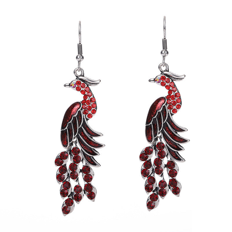 Red and silver feather-shaped earrings on a white background