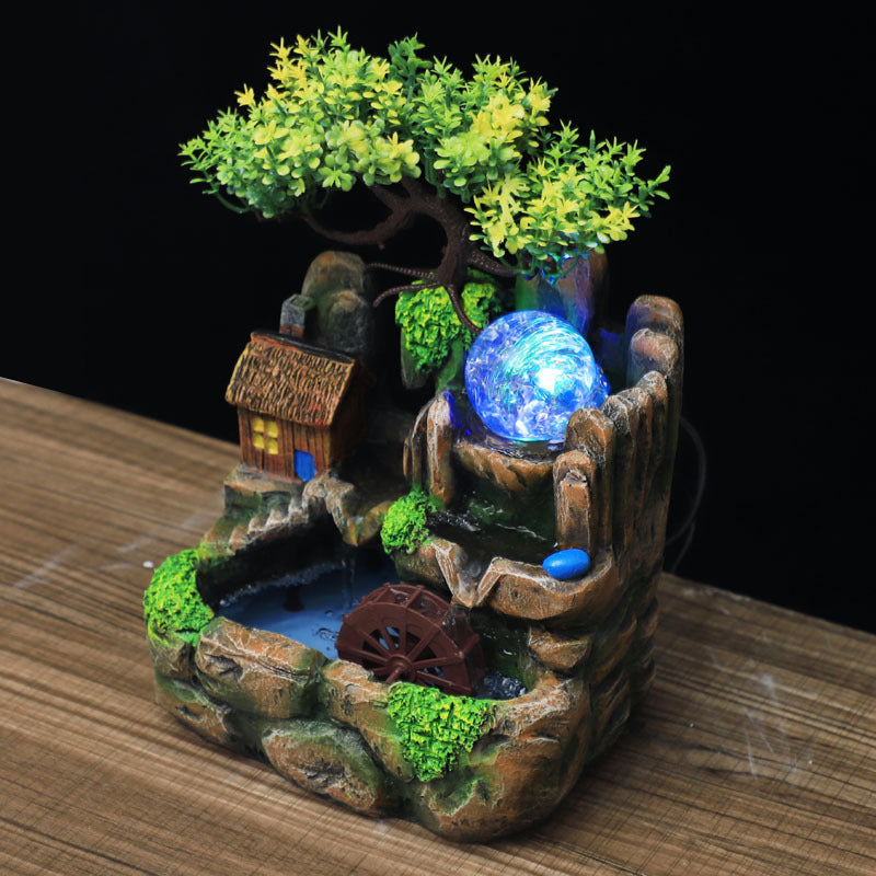 Decorative fountain with a glowing blue sphere on a wooden surface