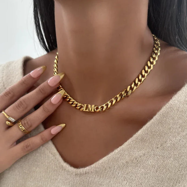 Gold chain necklace worn by a person with a neutral background