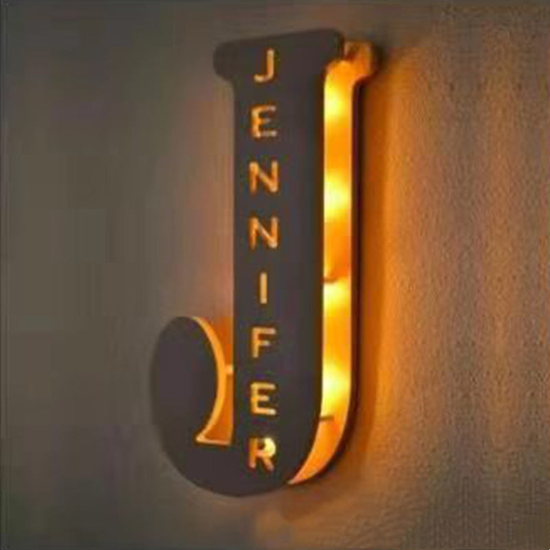 Decorative wall sconce with 'JENNIFER' on a textured wall