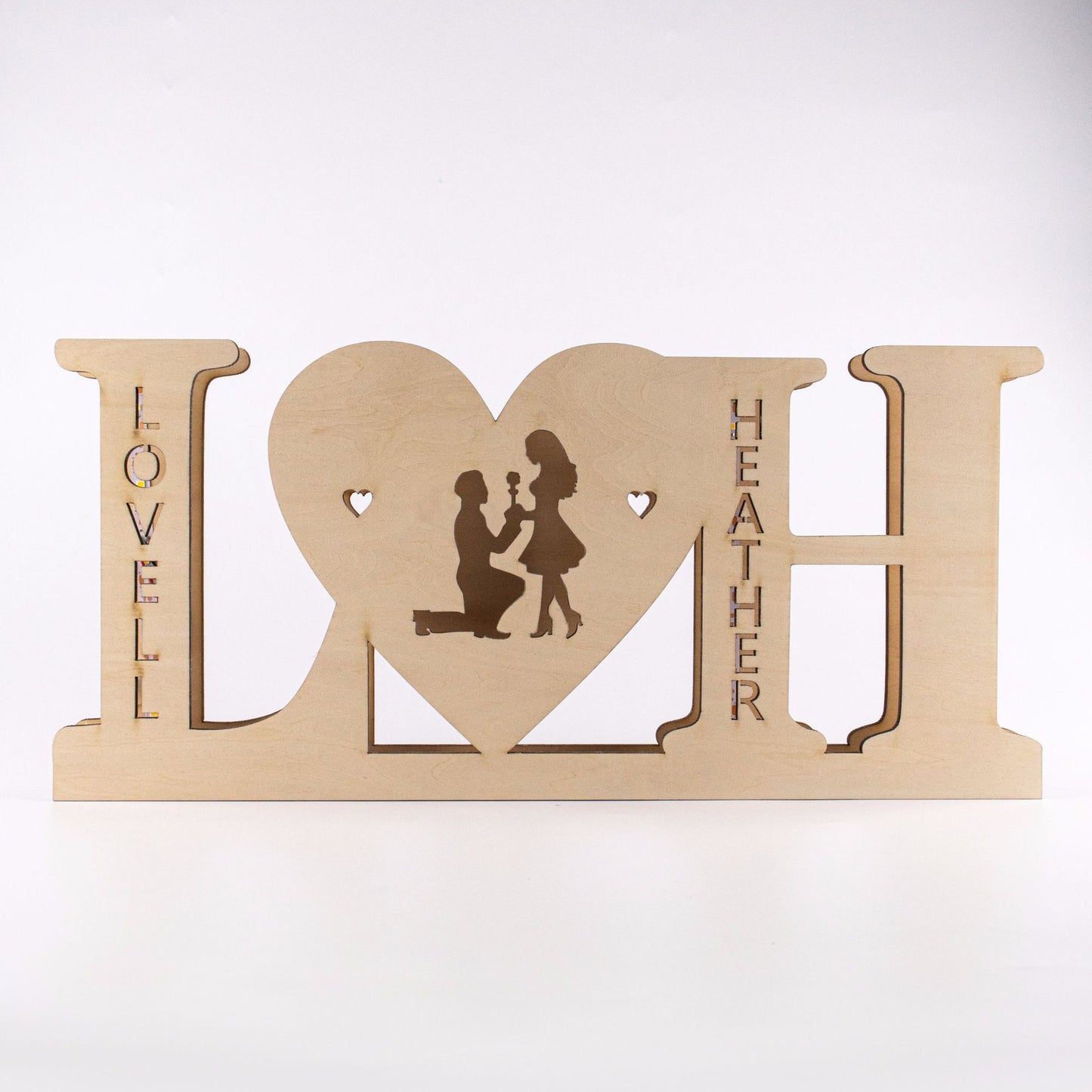 Wooden decorative sign with 'LOVE' and 'HEATHER' engraved, featuring a silhouette of a couple.