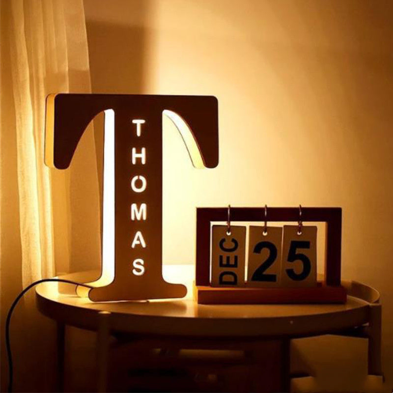 Decorative letter 'T' with 'THOMAS' on a small round table next to a calendar showing December 25th.