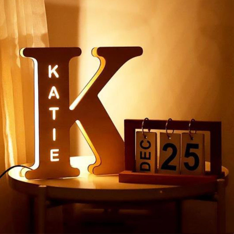Decorative letter 'K' with 'KATIE' on a wooden stand next to a calendar showing December 25th.